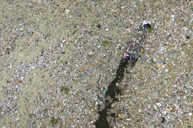 Na salvadorskem rezervoarju Cerron Grande v mestu Potonico moški zbirajo odpadno plastiko, steklo in druge materiale. Ogromne raznobarvne plastične usedline, ki priplavajo iz različnih pritokov, kot odeja prekrivajo mirne vode jezera Suchitlan. Enako se dogaja na rajskih plažah honduraškihh Karibov, na katere iz Gvatemale prihaja na tisoče ton odpadkov. Foto: Camilo Freedman/Afp