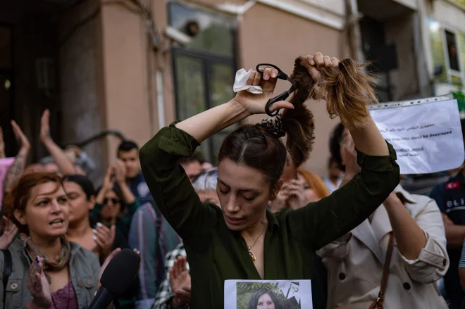 Nasibe Samsaei, Iranka, ki živi v Turčiji, si je med protestom pred iranskim konzulatom v Istanbulu odrezala dolge lase, potem ko je 22-letna Iranka Mahsa Amini umrla po aretaciji policije v Teheranu. Mahsa je bila z družino na obisku v Teheranu, ko jo je 13. septembra priprla policija, pristojna za izvajanje strogega iranskega kodeksa oblačenja za ženske, vključno z nošenjem naglavne rute v javnosti. Državna televizija jo je 16. septembra razglasila za mrtvo, potem ko je bila tri dni v komi. Foto: Yasin Akgul/Afp