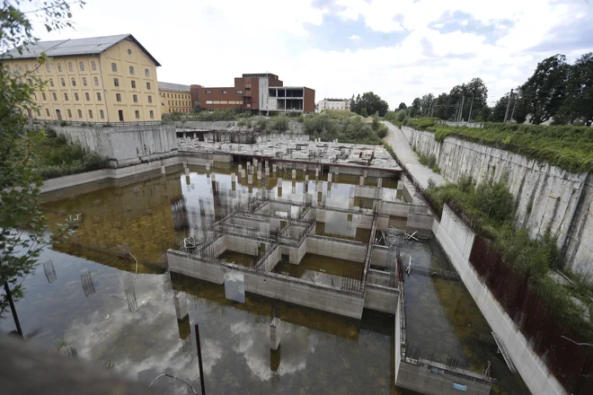 Družba AS57, ki je kupila kompleks 49 nepremičnin na območju Tobačne, ni nikoli razkrila, kaj na tem območju sploh načrtujejo. Medtem gradbeno jamo zaliva voda. FOTO:&nbsp;Leon Vidic/Delo
