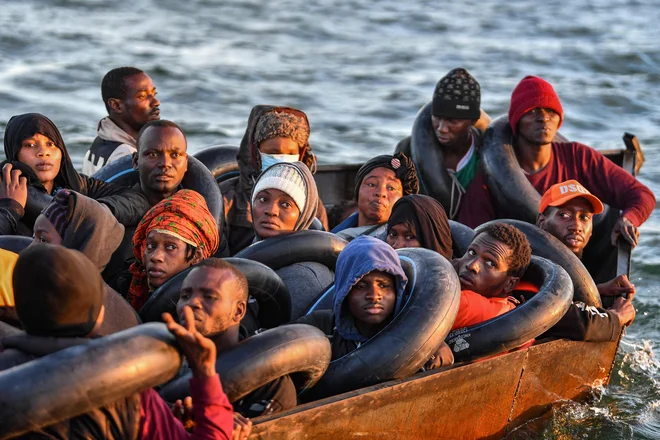 Migranti iz podsaharske Afrike sedijo v doma narejenem čolnu, s katerim so se skrivaj prebijali proti italijanski obali, ko so jih tunizijske oblasti našle ob obali osrednjega tunizijskega mesta Sfax, približno 50 navtičnih milj. Foto: Fethi Belaid/Afp