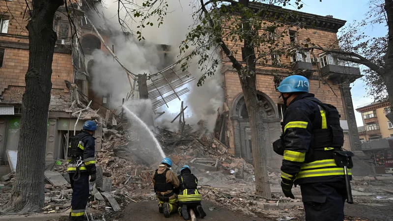 Fotografija: Reševalci na prizorišču, kjer so zjutraj ruske rakate zadele stavbe. FOTO: Reuters