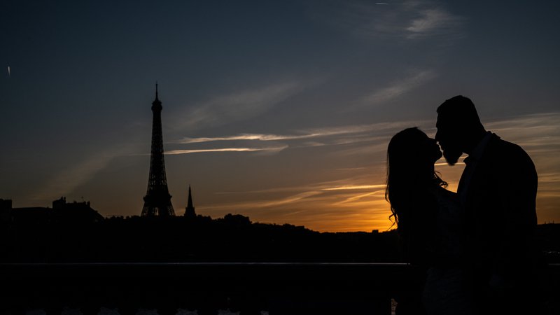 Fotografija: Par se poljublja ob sončnem zahodu v bližini Eifflovega stolpa v Parizu. Foto: Martin Bureau/Afp
