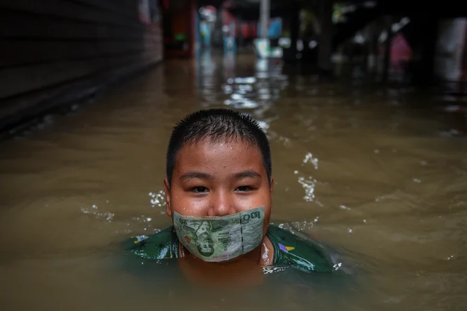 Tajski deček se igra na poplavljeni cesti po obilnem deževju v bližini mošeje Tha-it na obrobju Bangkoka. Foto: Chalinee Thirasupa/Reuters
