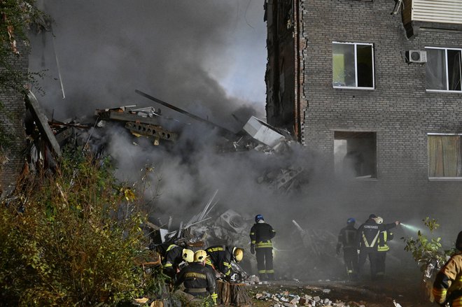 Reševalci delajo na prizorišču, potem ko so eksplozije hudo poškodovale stavbo v Zaporožju. FOTO: Reuters
