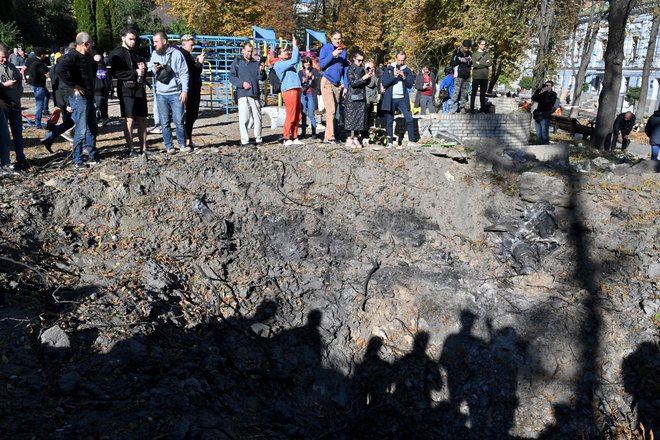 Krater po eksploziji rakete ob otroškem igrišču v Kijevu. FOTO: Sergei Supinsky/AFP
