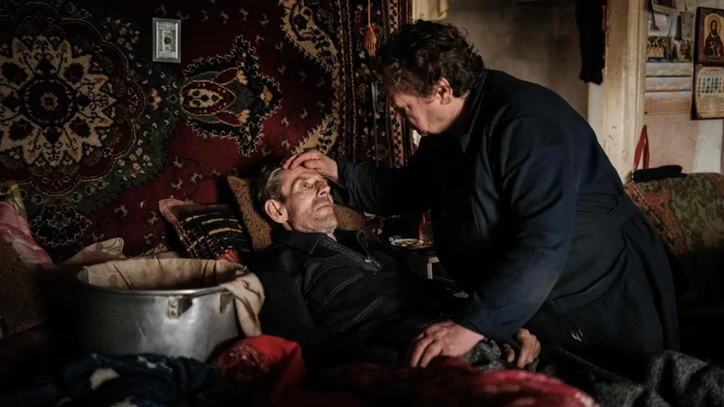 Fotografija: 67-letna Oleksandra neguje svojega 66-letnega moža Nikolaja, ki so mu pred petimi meseci diagnosticirali raka na pljučih, ob loncu, postavljenem na njuni postelji, v katerem se zbira voda iz strehe, poškodovane zaradi obstreljevanja njunega doma brez osnovnih storitev v frontnem mestu Bakhmut v regiji Doneck. Vinogradniško in solinarsko naselje Bakhmut še vedno držijo in mračno branijo ukrajinske sile, vendar so njegovi obupani prebivalci že od maja na dosegu ruskega orožja. Foto: Yasuyoshi Chiba/Afp