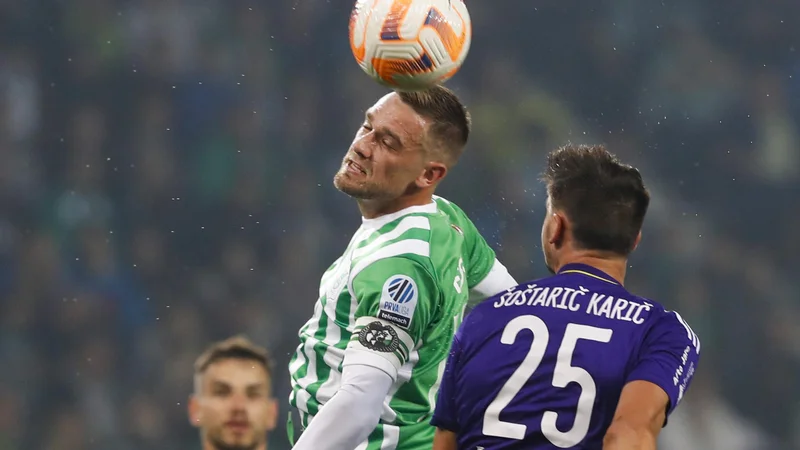 Fotografija: Vijolični Sven Šoštarič Karić (številka 25) je moral zaradi rdečega kartona predčasno končati derbi, zeleno-beli kapetana Timija Maxa Elšnika (levo v skoku) pa so slavili po enajstmetrovki v finišu tekme. FOTO: Matej Družnik