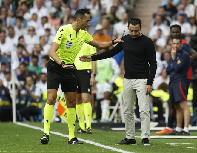 Glavni sodnik Jose Maria Sanchez Martinez v pogovoru s trenerjem Barcelone Xavijem Hernandezom.&nbsp;FOTO: Susana Vera/Reuters
