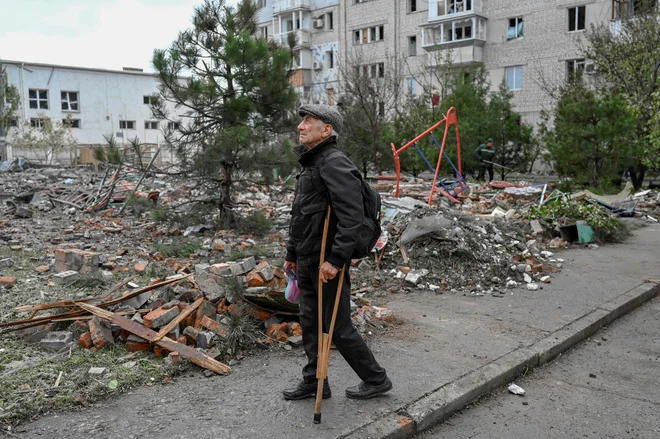 Moški stoji na ulici po raketnem napadu v Mikolajevu 23. oktobra. FOTO: Bulent Kilic/AFP
