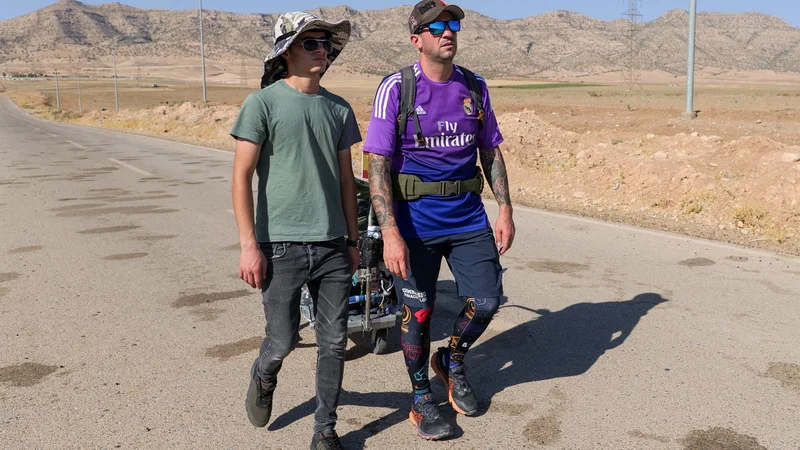 Fotografija: Santiago Sanchez se je na pot podal z vozičkom, na katerem vleče kovček s šotorom, tabletami za dezinfekcijo vode in kuhalnikom. Fotografija je nastala v iraškem Kurdistanu. FOTO: Charlotte Bruneau/Reuters
