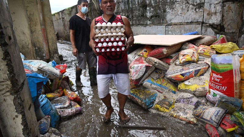 Fotografija: Ljudje se trudijo preživeti. Poplave so uničile veliko zalog hrane, tudi vreče riža. FOTO: Ted Aljibe/AFP
