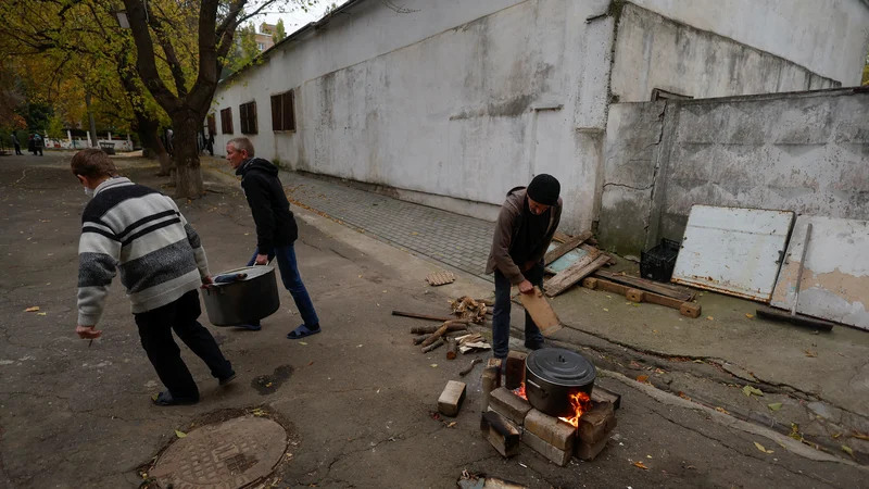 Fotografija: Zaposleni v enem izmed vrtcu v Mikolajevu med izpadom električne energije zaradi ruskega raketnega napada kuhajo hrano na drva.

FOTO: Valentin Ogirenko/Reuters
