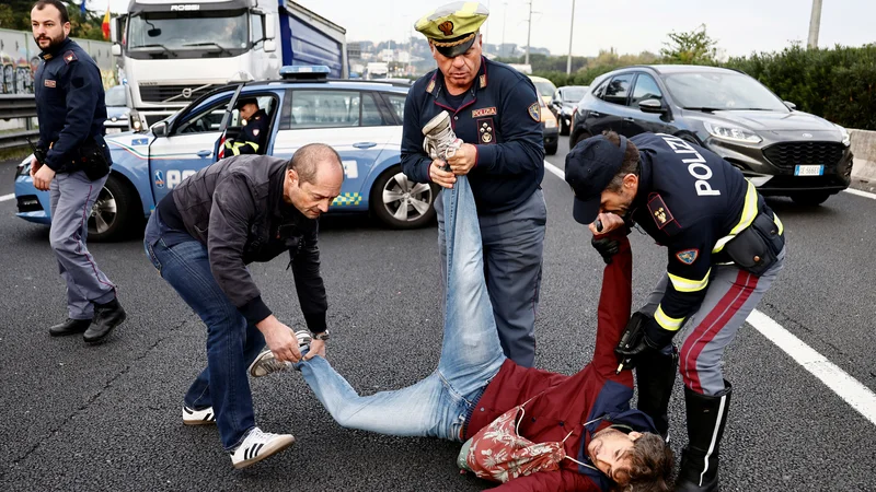 Fotografija: Policisti se trudijo odstraniti moškega iz ceste v Rimu, medtem ko italijanski podnebni aktivisti »Ultima Generazione« blokirajo avtocesto in opozarjajo na potrebo po boju proti podnebni krizi. Foto: Yara Nardi/Reuters