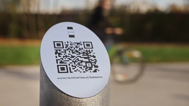 QR-koda s pripisom www.nevidnehise.si/baldahin je nameščena na začetku Lattermanovega drevoreda – pred rolkarskim parkom in parkiriščem v parku Tivoliju in s pogledom proti razrušenemu kopališču Ilirija. FOTO: arhiv Odprtih hiš Slovenije
