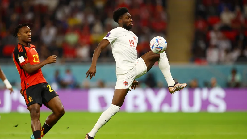 Fotografija: Alphonso Davies (desno) ima pestro življenjsko zgodbo, na uvodu mundiala pa je proti Belgiji zastreljal enajstmetrovko. FOTO: Kai Pfaffenbach/Reuters
