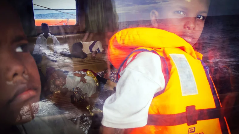 Fotografija: Osemletni Samir iz Somalije gleda skozi okno reševalne ladje Astral nevladne organizacije Proactiva Open Arms, ko se s hitrostjo 35 vozlov odpravljajo proti italijanskemu otoku Lampedusa, potem ko so jih rešili na morju. Libija s svojimi 1770 kilometri obale je postala središče nezakonitega preseljevanja proti Evropi, saj v državi, ki jo je zajel kaos, ni ustreznega mejnega nadzora. Migranti se v provizoričnih čolnih odpravljajo proti italijanskemu otoku Lampedusa, ki je od obale oddaljen približno 300 kilometrov. Foto: Ricardo Garcia Vilanova/Afp