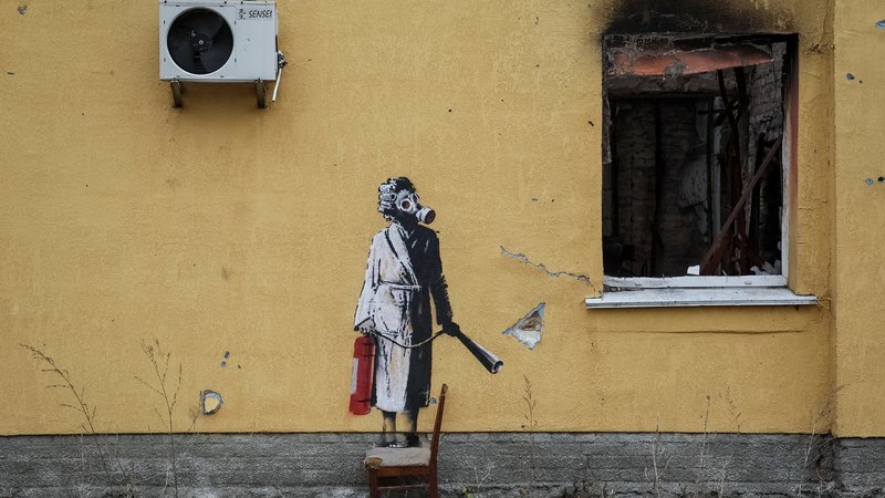 Fotografija: Banksy na steni v kraju Gostomel. Ženska z gasilnim aparatom in plinsko masko. FOTO: Gleb Garanich/Reuters
