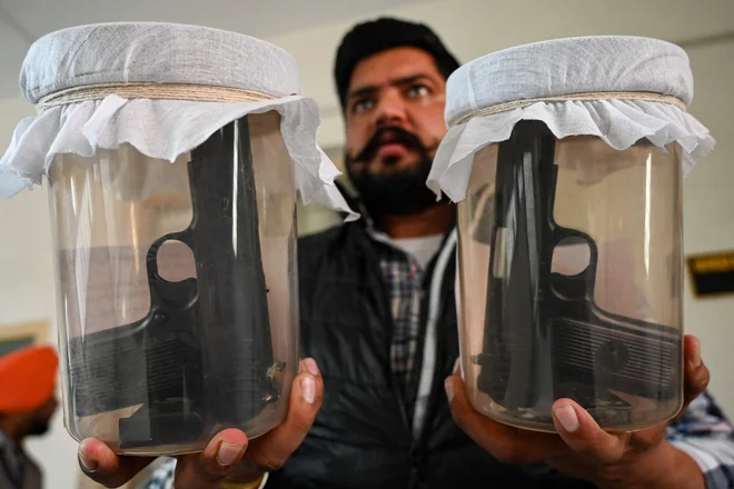 Član posebne policijske enote (STF) pandžabske policije na tiskovni konferenci v Amritsarju kaže najdeno orožje in heroin, ki so ga iz Pakistana odvrgla brezpilotna letala. Foto: Narinder Nanu/Afp