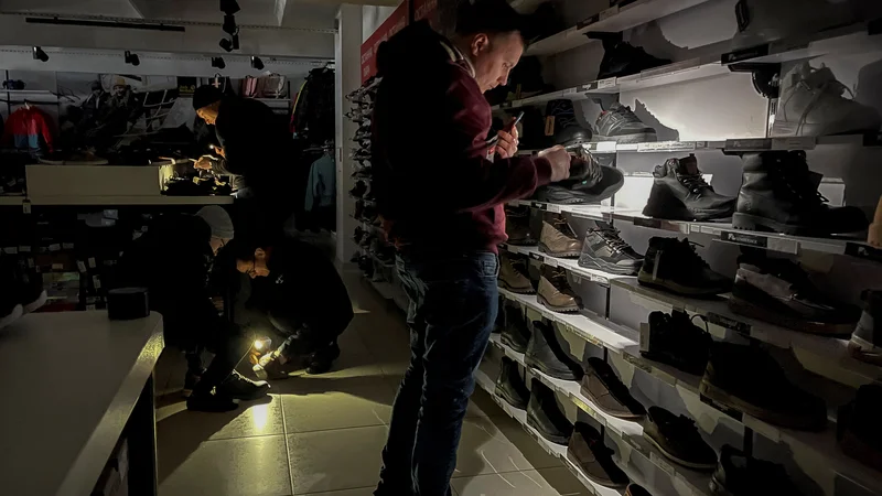 Fotografija: Prizor iz trgovine s čevlji v Kijevu, kjer zaradi uničene energetske infrastrukture občasno prihaja do izpadov preskrbe z elektriko. Foto: Gleb Garanich Reuters