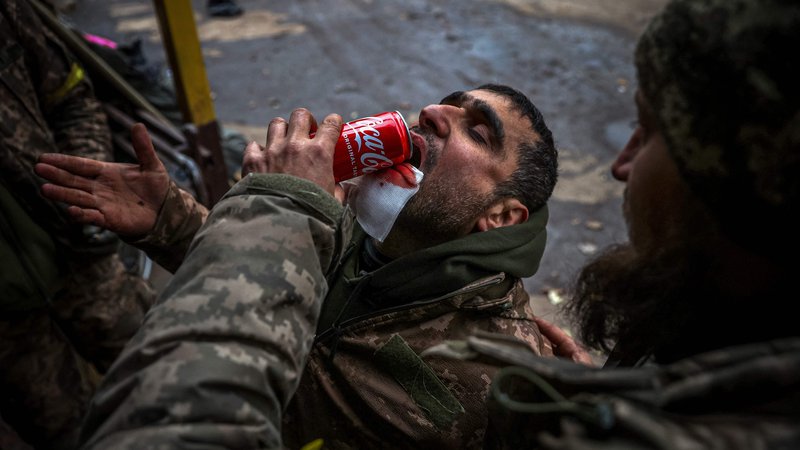 Fotografija: Ukrajinski vojak pomaga ranjenemu tovarišu piti med evakuacijo v  mobilni bolnišnici v okolici Bakhmuta v regiji Doneck  med rusko invazijo na Ukrajino. Foto: Anatolij Stepanov/Afp
