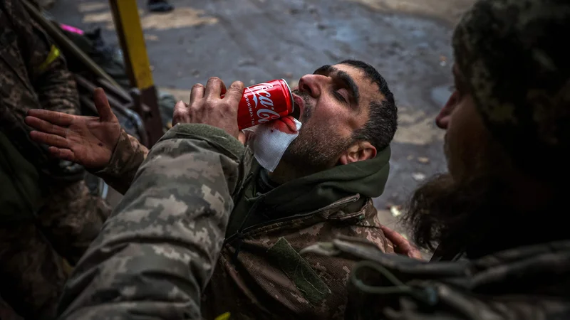 Fotografija: Ukrajinski vojak pomaga ranjenemu tovarišu piti med evakuacijo v mobilni bolnišnici v okolici Bakhmuta v regiji Doneck med rusko invazijo na Ukrajino. Foto: Anatolij Stepanov/Afp
