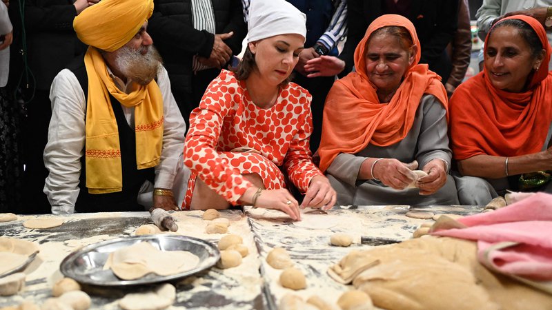 Fotografija: Nemška ministrica za zunanje zadeve Annalena Baerbock med pripravo indijskega kruha v javni kuhinji v sikhovski molilnici v New Delhiju, ki jo je obiskala med dvodnevnim obiskom v Indiji. FOTO: Sajjad Hussain/AFP
