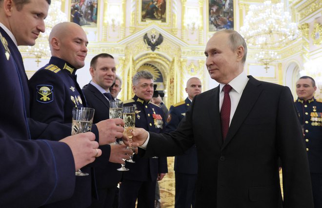 Ruski voditelj Vladimir Putin nazdravlja s pripadniki vojske med podelitvijo vojaških priznanj. Foto Mikhail Metzel/AFP

