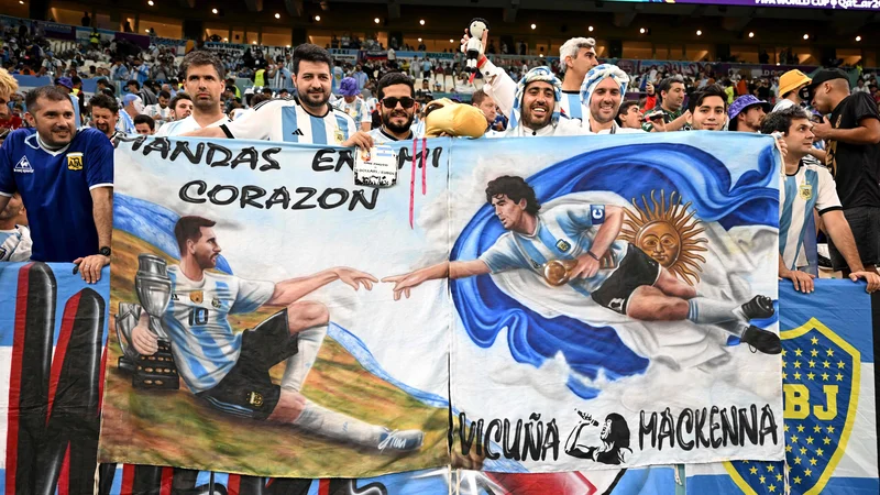 Fotografija: Argentinski navijači so med tekmo s Hrvaško povezali legendarna nogometaša z zastavo: levo Lionel Messi, desno Diego Maradona. FOTO: Manan Vatsyayana/AFP