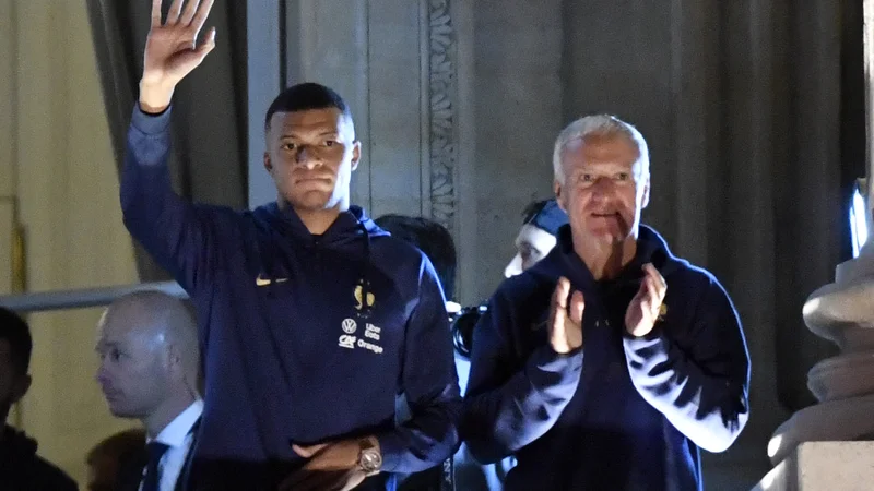 Prvi zvezdnik reprezentance Kylian Mbappe s selektorjem Didierjem Deschampsom pozdravlja navijače s terase hotela Crillon na trgu Concorde v središču Pariza. FOTO:&nbsp;Julien De Rosa/AFP
