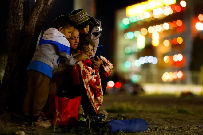 Sugeidy Medina, venezuelska migrantka, ki bo z otroki in možem ZDA zaprosila za azil gleda na mobilni telefon ob reki Rio Bravo, na meji med Mehiko in ZDA. Foto: Jose Luis Gonzalez/Reuters