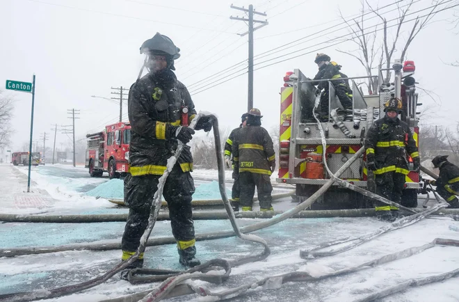 Gasilci med odstranjevanjem ledu z opreme pri gašenju požara v Detroitu. FOTO: Matthew Hatcher/Getty Images via AFP
