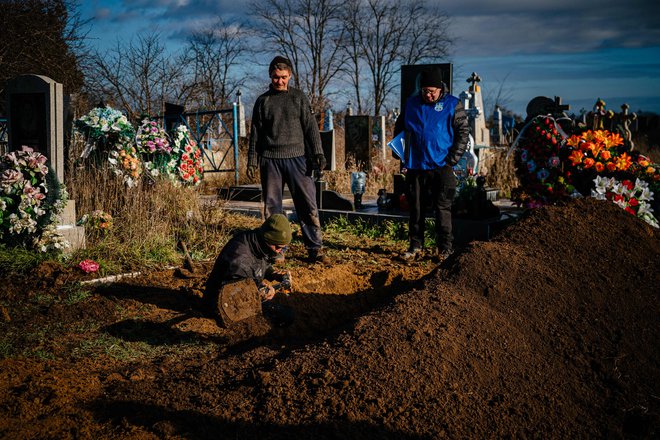 Preiskovalci vojnih zločinov skupaj z lokalnim prebivalstvom v bližini Hersona iz groba odstranjujejo posmrtne ostanke ženske, ubite med rusko invazijo. Foto: Dimitar Dilkoff/Afp
