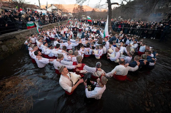 Bolgarski moški so danes zjutraj plesali tradicionalni ples »horo« v mrzli reki Tunjice v mestu Kalofer v okviru praznovanja pravoslavnega božiča. Po tradiciji pravoslavni duhovnik v reko vrže križ in verjame se, da bo tisti, ki ga dobi nazaj, vse leto zdrav, prav tako pa tudi vsi tisti, ki plešejo v ledenih vodah. Foto: Nikolay Doychinov/Afp
