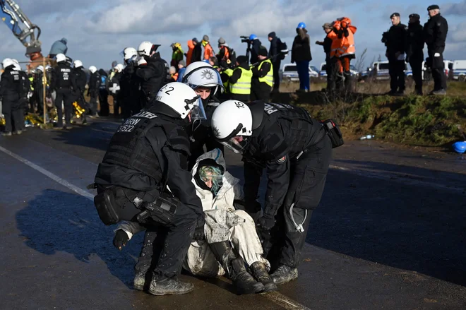 Policisti v nemškem&nbsp;Lützerathu odnašajo protestnike, ki se borijo proti porušenju naselja zaradi razširitve odkopa rjavega premoga.&nbsp;&nbsp;FOTO:&nbsp;Ina Fassbender/AFP
