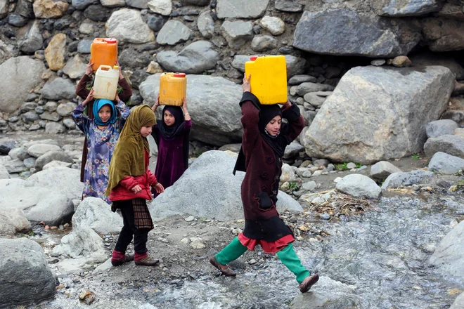 Afganistanska dekleta nosijo kanistre s pitno vodo, ki so jo napolnile iz potoka v okrožju Dara-i-Nur v provinci Nangarhar. Foto: Shafiullah Kakar/Afp