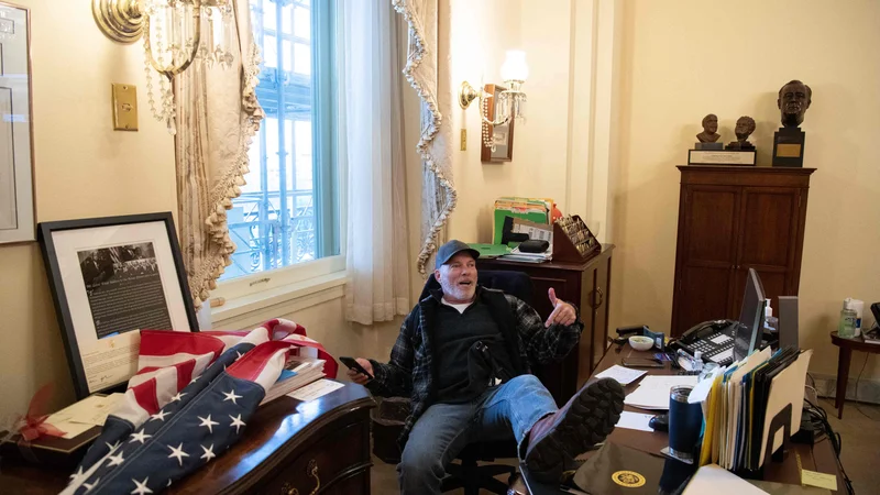 Fotografija: Fotografija, ki je obkrožila svet: Barnett z ameriško zastavo v roki, z nogami na pisalni mizi Nancy Pelosi. Foto Saul Loeb/AFP