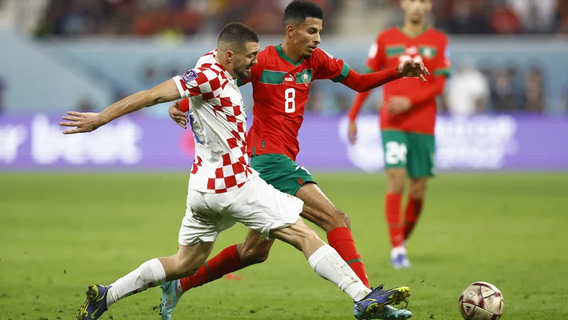 Fotografija: Hrvaški vezist Mateo Kovačić ustavlja Azzedineja Ounahija med tekmo za tretje mesto na SP 2022 v Katarju. FOTO: Peter Cziborra/Reuters