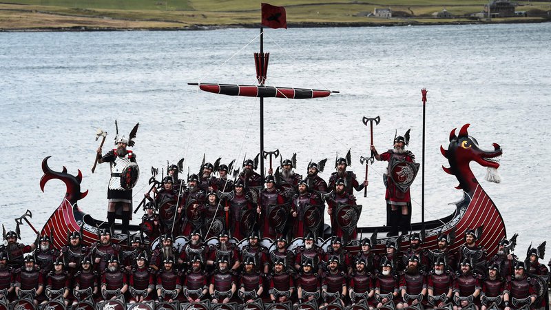 Fotografija: Člani skupine Jarl Squad pozirajo s svojo vikinško ladjo v Lerwicku na Šetlandskih otokih pred uradnim začetkom festivala »Up Helly Aa«. Up Helly Aa praznuje vpliv skandinavskih Vikingov na Šetlandskih otokih, vrhunec pa se zgodi, ko se stemni in 1000 »guizerjev« (moški v kostumih), meče goreče bakle v svoj vikinški čoln, ki ga na koncu zažgejo. Foto: Andy Buchanan/Afp
