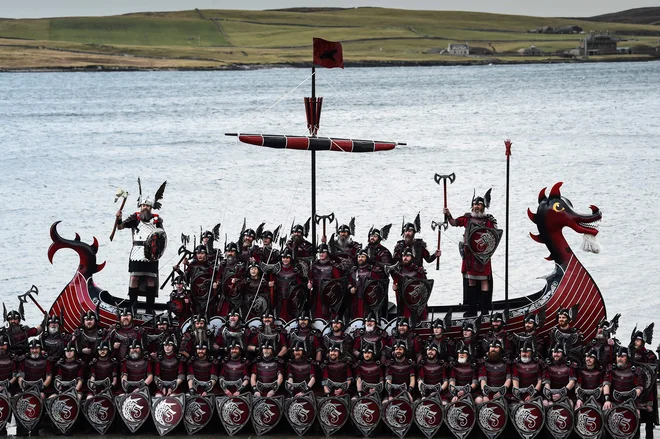 Člani skupine Jarl Squad pozirajo s svojo vikinško ladjo v Lerwicku na Šetlandskih otokih pred uradnim začetkom festivala »Up Helly Aa«. Up Helly Aa praznuje vpliv skandinavskih Vikingov na Šetlandskih otokih, vrhunec pa se zgodi, ko se stemni in 1000 »guizerjev« (moški v kostumih), meče goreče bakle v svoj vikinški čoln, ki ga na koncu zažgejo. Foto: Andy Buchanan/Afp