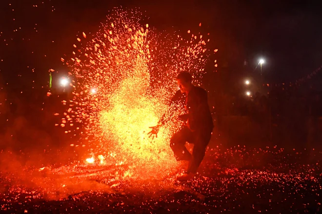 Moški iz etnične skupine Pa Then med obredom ognjenega plesa v gorati provinci Tuyen Quang na severu Vietnama skače po gorečem premogu. Etnična skupina verjame, da lahko ta tradicionalni moški obred plesa z ognjem pomaga pregnati demone in prinese dobro letino. Foto: Nhac Nguyen/Afp