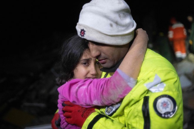 Policist objema svojo hčerko, potem ko so jo rešili izpod ruševin. FOTO: Bulent Kilic/AFP
