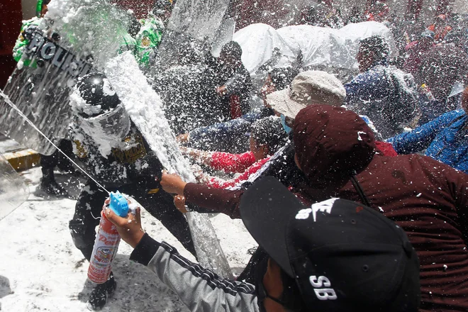 Perujci se spopadajo s policijo na demonstracijah proti perujskemu predsedniku Dinu Boluarteju, tako, da jih škropijo s peno in vodo, kar je karnevalski običaj v mestu Puno. Foto: Juan Carlos Cisneros/Afp