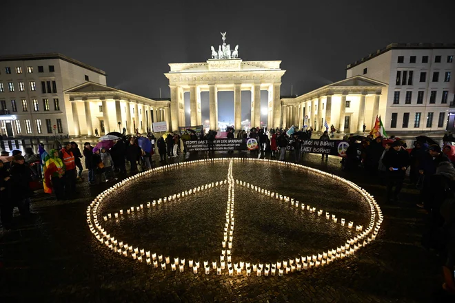 Pred Brandenburškimi vrati v Berlinu so včeraj iz sveč oblikovali velikanski znak miru ob današnji prvi obletnici ruske invazije na Ukrajino. Foto: Tobias Schwarz/Afp