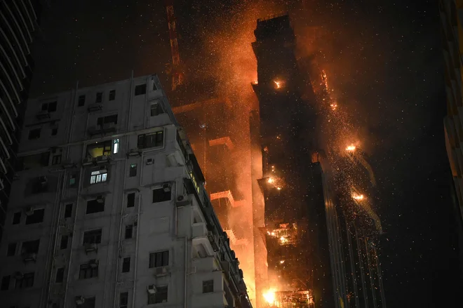 V četrtek zvečer je v Hongkongu izbruhnil velik požar. Plameni so goltali zgornja nadstropja stolpnice v priljubljeni nakupovalni četrti. Nebotičnik je bil še v izgradnji, zato je ob nadstropjih zagorel tudi gradbeni oder. V zraku so lebdeli goreči ostanki. Zaradi požara so morali iz sosednjih stavb evakuirati 170 oseb, dve pa so prepeljali v lokalno bolnišnico. Foto: Peter Parks/Afp