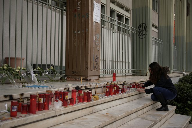 A woman lights candles placed at the entrance of the courthouse, following the fatal collision of two trains, in the city of Larissa, Greece, March 4, 2023. REUTERS/Giannis Floulis Foto Giannis Floulis Reuters
