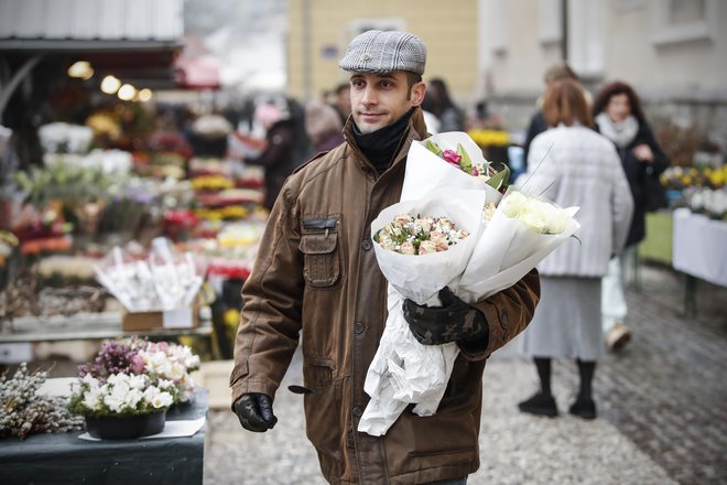 Stojnica z rožami v Ljubljsni in moški, ki je kupil šopek. FOTO: Uroš Hočevar/Delo
