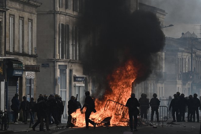 Policisti za boj proti izgredom ob ognju, ki so ga zanetili protestniki med demonstracijami. FOTO: Philippe Lopez/AFP
