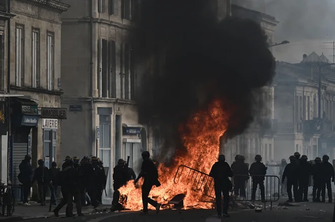 Policisti za boj proti izgredom ob ognju, ki so ga zanetili protestniki med demonstracijami. FOTO: Philippe Lopez/AFP
