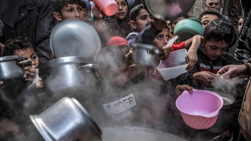 Fotografija: Na ulici v Gazi otroci držijo lonce in posode za juho, ki jo je pripravil Palestinec Walid al-Hattab, med postom na drugi dan muslimanskega svetega meseca ramadan. Foto: Mohammed Abed/Afp
