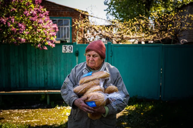 Ukrajinka drži kruh iz humanitarne pomoči pred svojo hišo v Siversku v regiji Doneck med rusko invazijo na Ukrajino. Foto: Dimitar Dilkoff/Afp